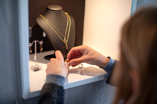 A jewelry store owner arranging her display case before opening up her store for business.