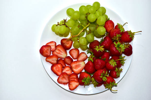 istock Grapes and large cut Victoria berries on a white plate 1251003194