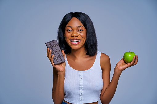 Slim woman with smile shows fruit and black chocolate