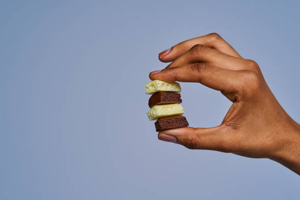 istock Female hand close-up with stack of chocolate pieces. Diet concept 1251003737