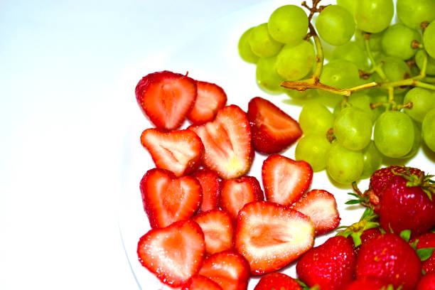 istock Grapes and large cut Victoria berries on a white plate 1251003811