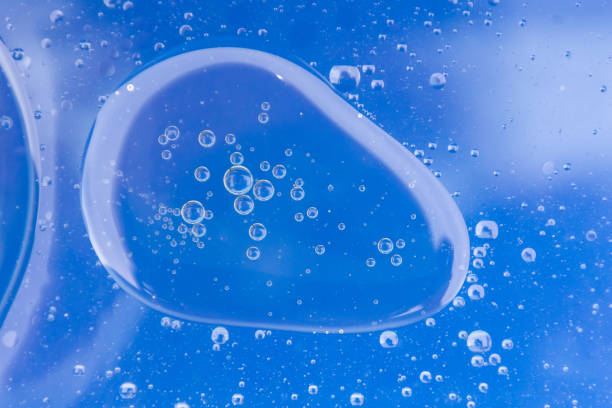 istock Large Oil bubbles grouped together in water with bright blue background. 1251004179