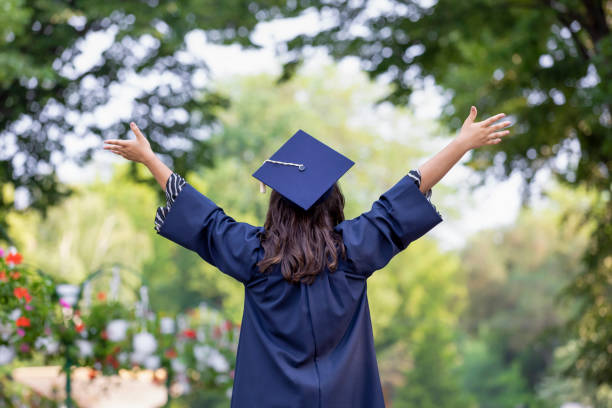 istock Back view of young woman graduating put her hands up 1251007236