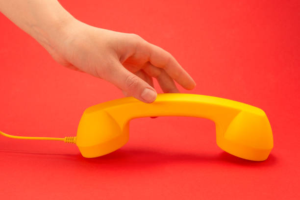 istock Yellow handset on a red background in woman hand. 1251007276