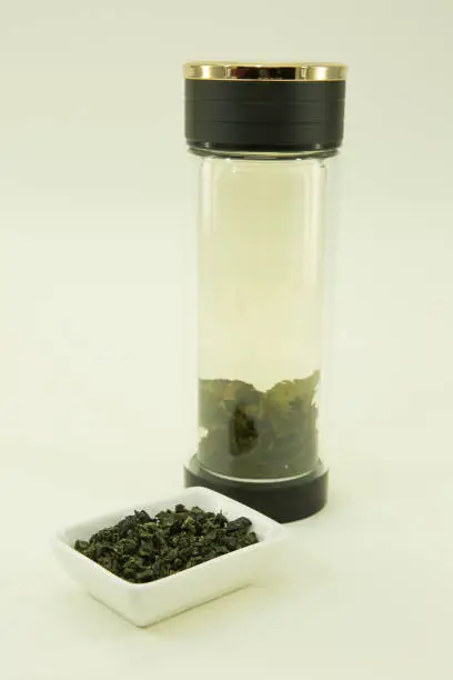 Photo of Chinese green tea. Milk Oolong Tea is brewed in a double glass thermo dish. Isolated in a white bowl on a white background