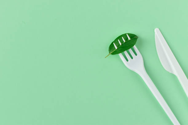 istock Fork and knife made of plastic on a green background. 1251007750