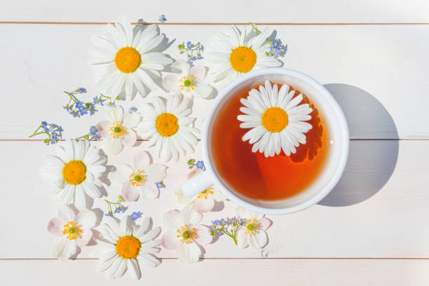 istock Chamomile tea in a white little cup on a light wooden surface. 1251011163