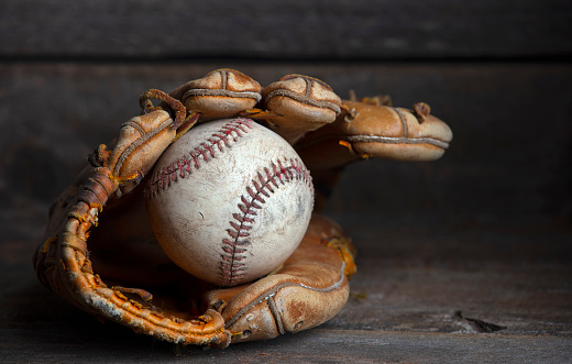 Baseball, leather glove and ball on pitch sand after fitness, workout or training for match or competition. Zoom, texture and softball mitt on field for sports team, wellness exercise or stadium game