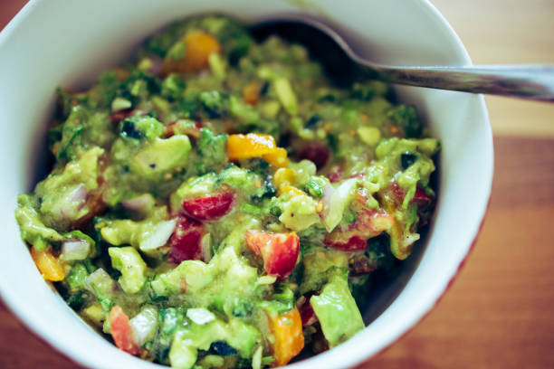 A green avocado with parsley on top sits on a white plate, healthy food