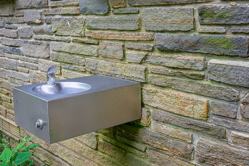 Horizontal shot of an outdoor drinking fountain in the Great Smoky Mountains National Park mounted to a stone wall.