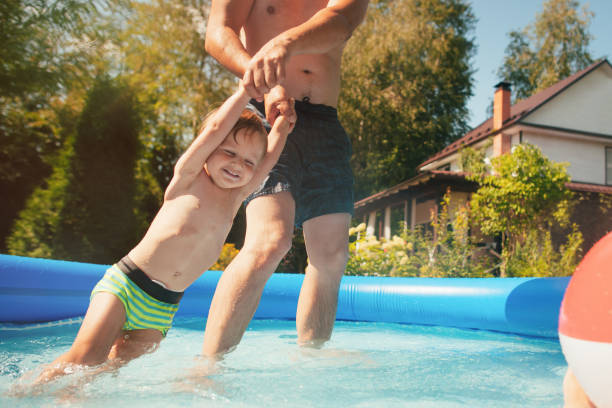 istock Little boy and his father having fun in pool at back yard 1251017905