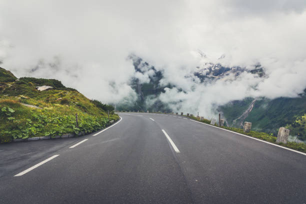istock Deep white clouds covering the green mountains and a road 1251020379