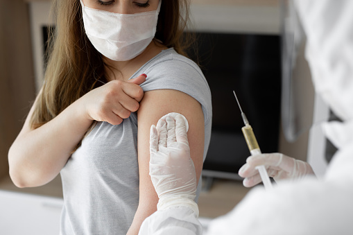 Médico en traje protector personal o EPI inyectar inyección vacuna para estimular la inmunidad de la paciente paciente en riesgo de infección por coronavirus. Coronavirus, covid-19 y concepto de vacunación photo