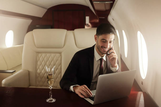 istock Billionaire or rich business man flying first class and working on plane with laptop and glass of champagne. Private jet concept 1251024320
