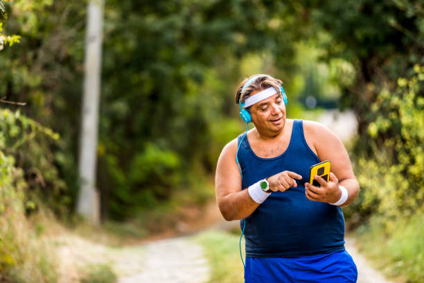 istock Overweight man using phone after exercises in the park. 1251027396