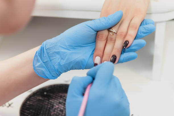 istock Manicure master in blue rubber gloves apply nail Polish client's nails 1251031688