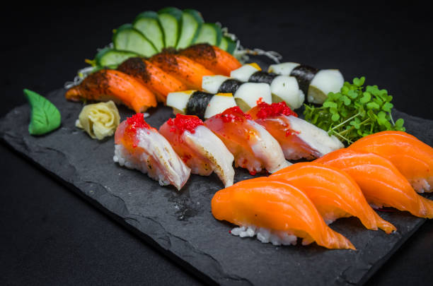 sushi, cocina tradicional japonesa. varios deliciosos sushi en el plato decorado, fondo negro. grupo de sushi, urakami, nigori, sushi jow, sashimi, tekamaki, etc... - niguiri sushi fotografías e imágenes de stock