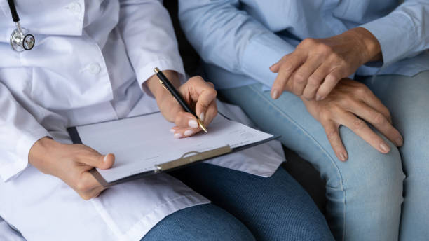 istock Closeup view nurse writing personal info listens elderly patient 1251044144