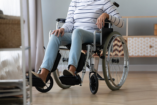 Unable to walk aged handicapped woman sitting in wheel chair cropped image view of old female lower body and invalid carriage, result of illness injury or disability healthcare rehabilitation concept