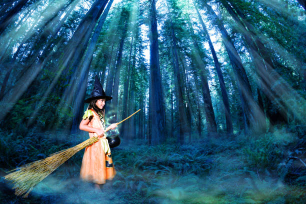 Girl in Halloween costume with broom and witch hat, bucket in enhanced magical forest