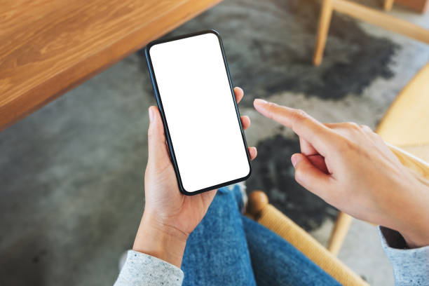 istock a woman holding and pointing finger at mobile phone with blank white desktop screen 1251055397