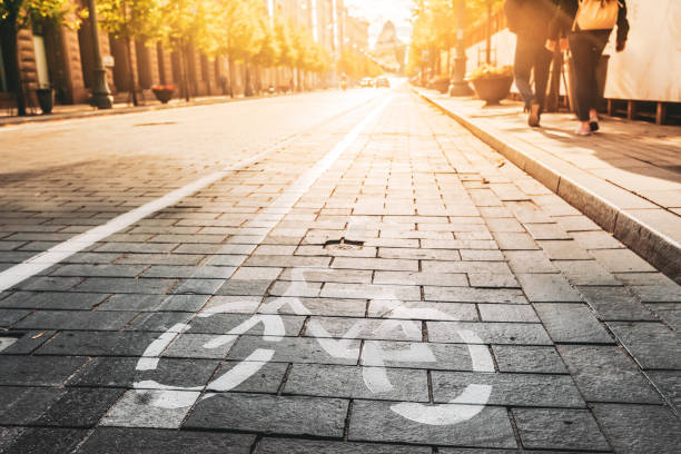 bycycle road sign, road marking of bicycle path along avenue or street in city in a sunny morning or evening at sunset or sunrise. concept of cycling trips - sunrise city of sunrise street road imagens e fotografias de stock