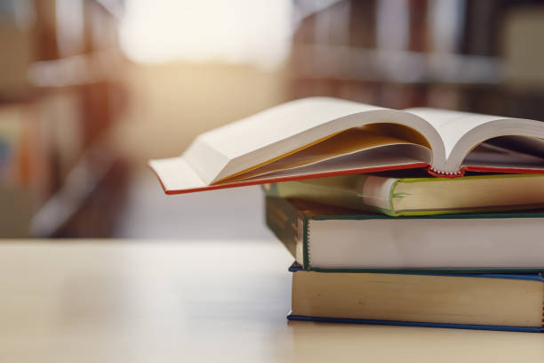 istock Open book on stack of books in library at school, university, college. 1251066760