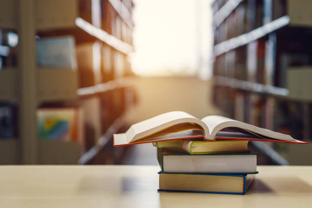 istock Open book on stack of books in library at school, university, college. 1251066825