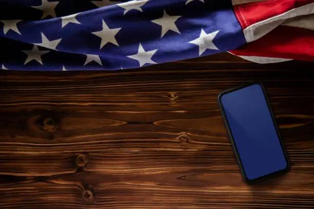 4th of July or Memorial Day of United States Concept. Blank Mobile Screen for Mockup. USA Flag Lying on Wooden Background. American Symbolic. Top View