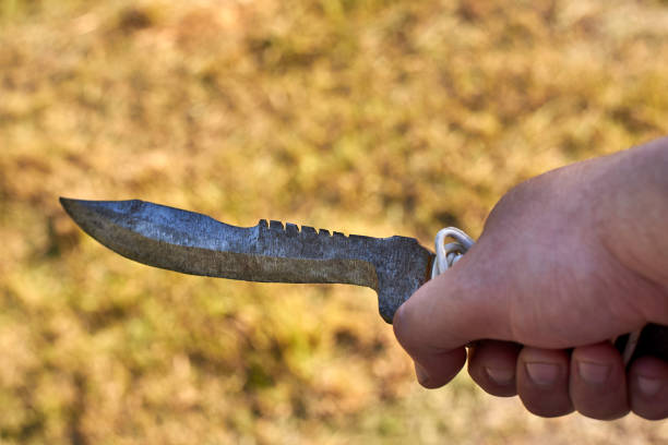 istock Old notch knife in man's hand on grass background. 1251076929