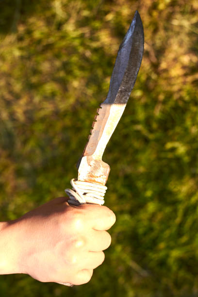 istock Old notch knife in woman's hand on grass background. 1251077443