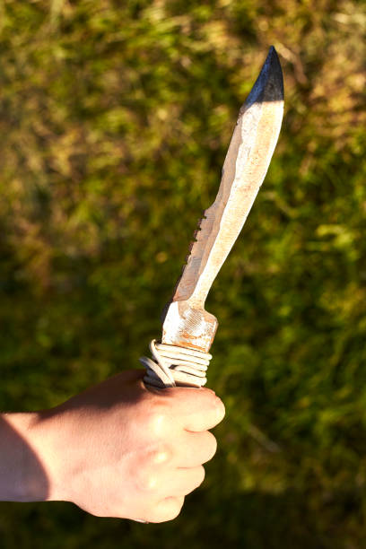 istock Old notch knife in woman's hand on grass background. 1251077449