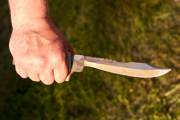 istock Old notch knife in man's hand on grass background. 1251077456