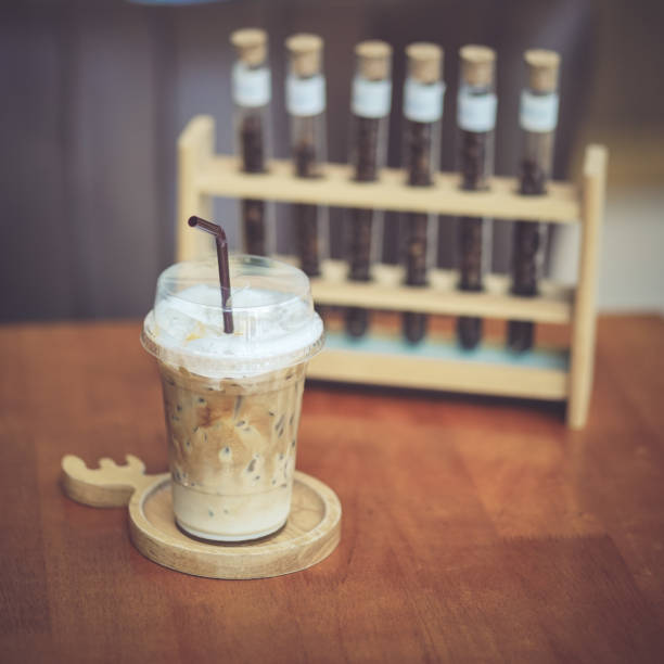 Vintage coffee. An iced caramel macchiato in plastic takeaway cup. Vintage filter and sligjt grained style.