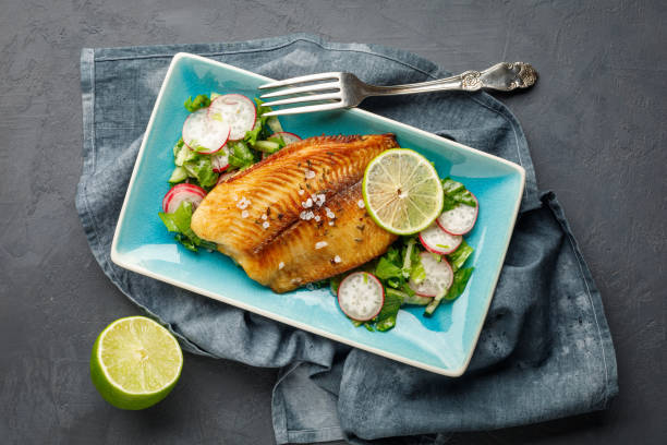 istock Grilled fish sea bass with fresh herbs, radish and lime in a rectangular blue plate. 1251084930