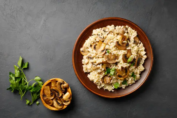Traditional italian cuisine meal - vegetarian risotto with mushrooms. Black stone backround.