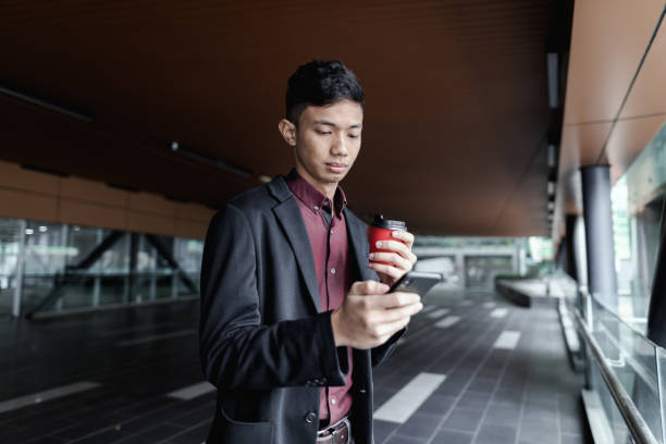 istock Asian casual businessman using phone with coffee cup on the go 1251087557
