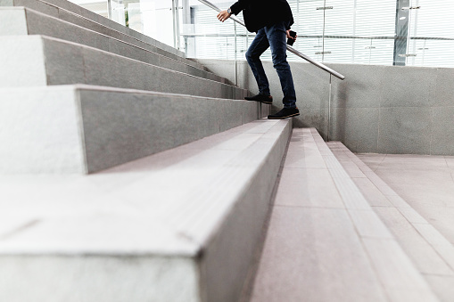 from the bottom of the handle is a recessed LED strip with yellow light. hidden built-in lamp shows a man's hand. the concrete side of the staircase with retaining walls  night, corridor, granite, included, under