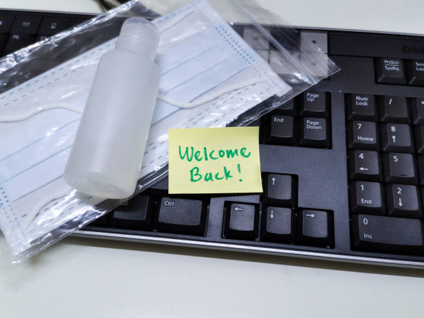 Welcome back note with hand sanitizer and mask on top of keyboard Welcome note with hand sanitizer and mask on work keyboard; Back to work note with alcohol gel to prevent coronavirus / infection prevention photos stock pictures, royalty-free photos & images