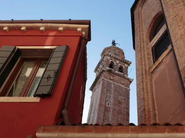 The bell tower of Santa Maria dei Carmini through a gap between buildings, Venice, Italy