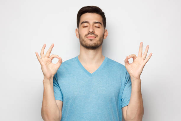 istock Concentrated relaxed man standing with closed eyes, having relaxation while meditating, trying to find balance and harmony isolated on gray. Yoga and meditation concept 1251099207