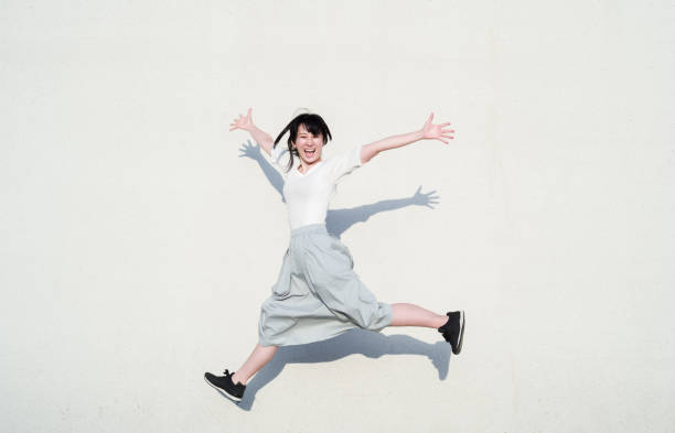 foto de la mujer asiática saltando con la sonrisa frente a la pared blanca - healthy lifestyle women jumping happiness fotografías e imágenes de stock