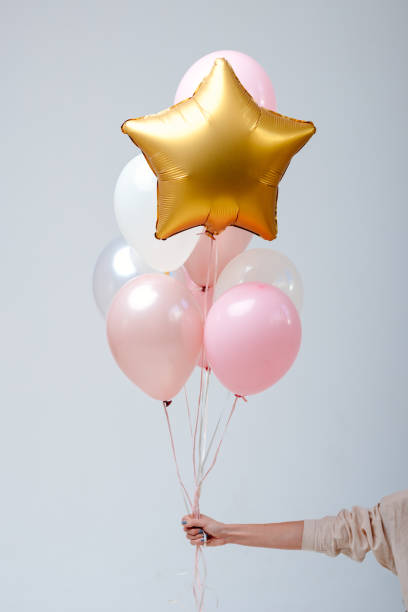 Composition of helium balloons Composition of white, pink, transparent helium balloons and gold star in the hand of a woman on a white background. helium balloon stock pictures, royalty-free photos & images
