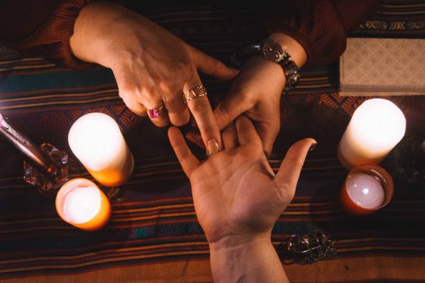 mujer leyendo las manos con joyas en los dedos y velas y una cubierta de tarot alrededor de la mesa. concepto de ocultismo - occultism fotografías e imágenes de stock