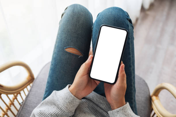 istock a woman holding mobile phone with blank desktop white screen while lying on a sofa at home 1251099414