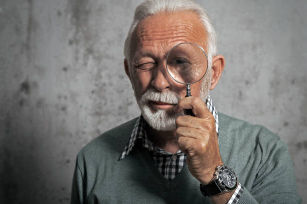 istock Mature man looking through a magnifying glass 1251107121