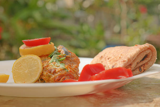 fish curry with roti mauritian mauritius indian plate dish food with lemon and sliced tomato