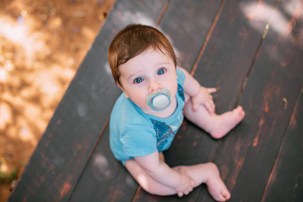 Blue and white baby pacifier standing on a white surface with a blurred blue background