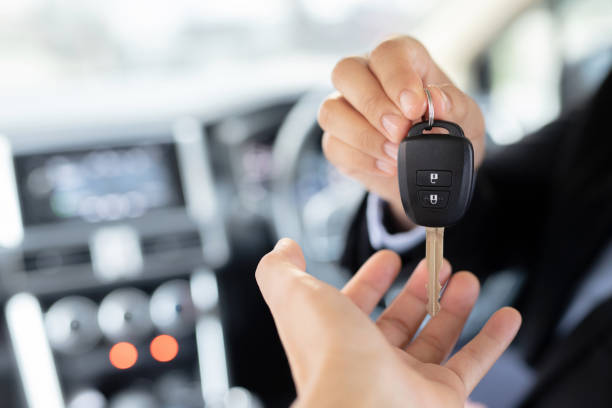 Staff is holding a new car key at the showroom. stock photo