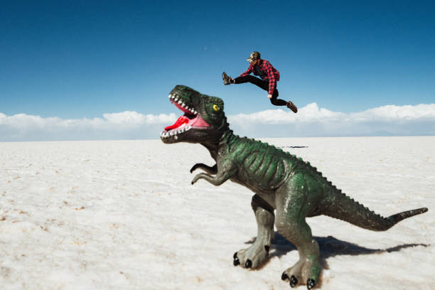 Tourist in Salt Flat Salar de Uyuni, funny photos, forced perspective Fun forced perspective shot of young man whos trying to fight with dinosaur at Uyuni Salt Flats (Spanish: Salar de Uyuni ) in Bolivia, South America. bolivia photos stock pictures, royalty-free photos & images